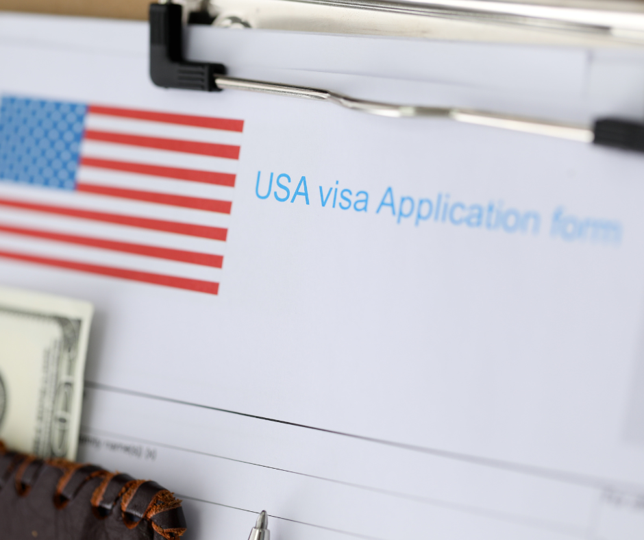 Differences between E1 and E2 Visas. Image of a US Visa application form alongside a US flag, a wallet containing money, and a pen.